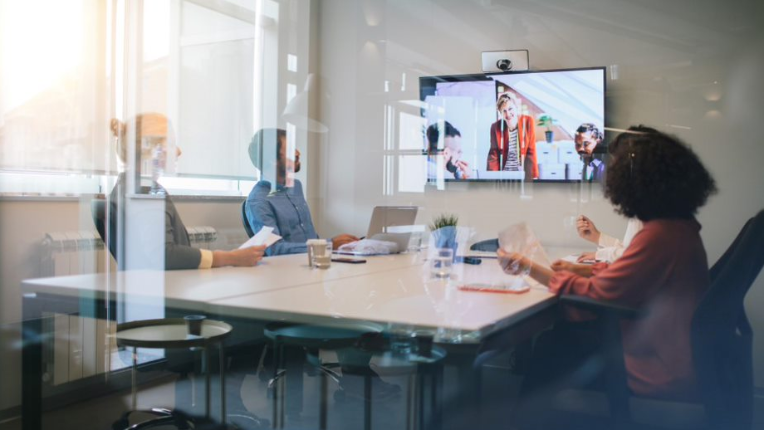 Team seated at table attending video conference